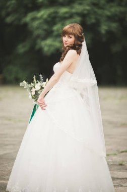 Çekici gelinin portresi, uzun saçlı, büyük buketli poz veren.