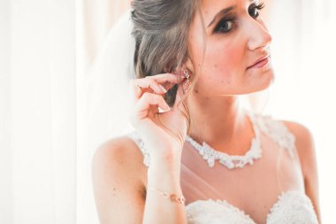 Cüppeli muhteşem gelin bir odada düğün töreni için poz veriyor ve hazırlanıyor.