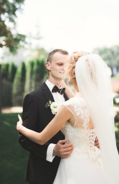 Yeni evli çiftimiz düğün günlerinde ellerinde buketle parkta yürüyorlar.