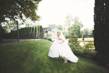 Parkta poz veren zarif beyaz elbiseli güzel gelin.