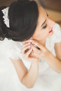 Cüppeli muhteşem gelin bir odada düğün töreni için poz veriyor ve hazırlanıyor.