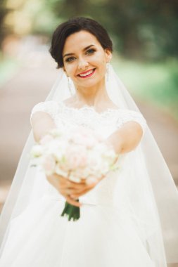 Çekici gelinin portresi, uzun saçlı, büyük buketli poz veren.