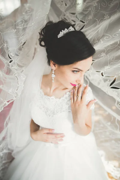 Preciosa novia en bata posando y preparándose para la ceremonia de boda cara en una habitación — Foto de Stock