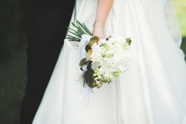 Gelin çiçekli büyük ve güzel bir düğün buketi tutuyor.