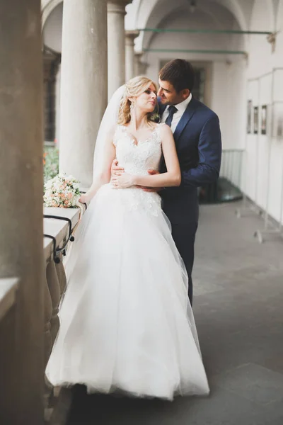 Прекрасная счастливая свадебная пара, невеста с длинным белым платьем позирует в красивом городе — стоковое фото