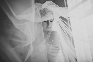 Cüppeli muhteşem gelin bir odada düğün töreni için poz veriyor ve hazırlanıyor.