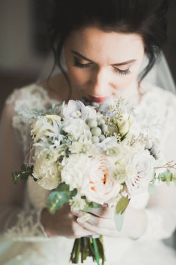 Beyaz elbiseli lüks gelin düğün törenine hazırlanırken poz veriyor.