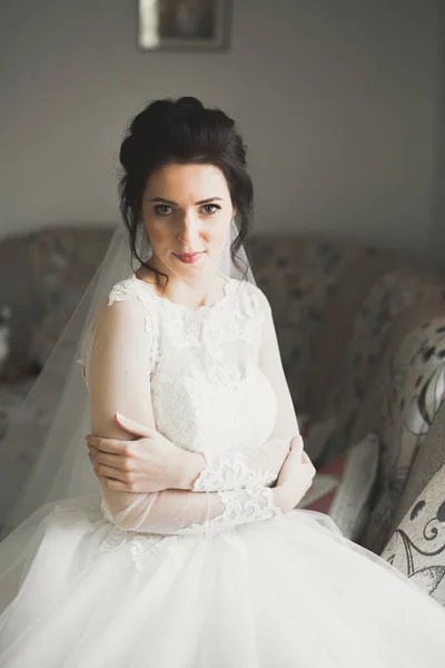 Hermosa novia con vestido de novia de moda con plumas con maquillaje de lujo deleite y peinado, estudio sesión de fotos interior — Foto de Stock