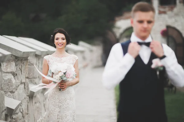 Stilvolles Brautpaar spaziert am Hochzeitstag mit Blumenstrauß durch den Park — Stockfoto