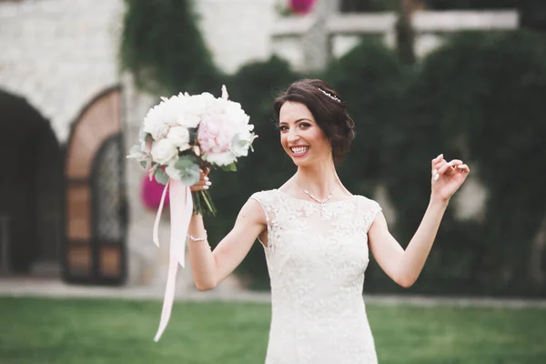 Beautiful bride in elegant white dress holding bouquet posing in park — Stock Photo, Image