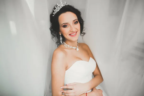 Preciosa novia en bata posando y preparándose para la ceremonia de boda cara en una habitación — Foto de Stock