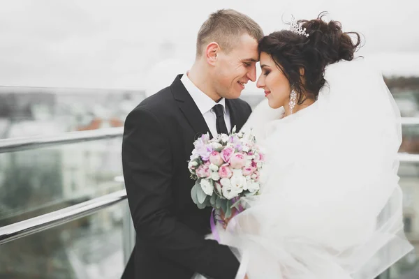 Casal feliz encantador do casamento, noiva com vestido branco longo posando na cidade bonita — Fotografia de Stock