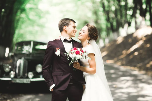 Стильна весільна пара, наречена, поцілунки і обійми на ретро автомобілі — стокове фото