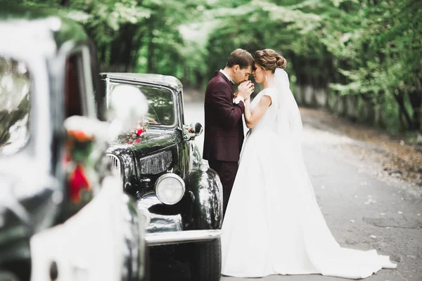 Beau couple nouvellement marié posant près de voiture noire rétro — Photo