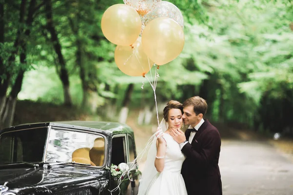 Güzel yeni evli çift siyah arabanın yanında poz veriyor. — Stok fotoğraf