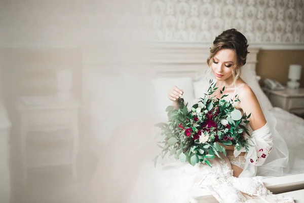 Hermosa novia con vestido de novia de moda con plumas con maquillaje de lujo deleite y peinado, estudio sesión de fotos interior —  Fotos de Stock