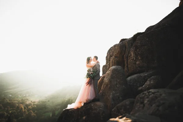 Glad vacker bröllop par brud och brudgum på bröllopsdagen utomhus på berget rock. Glada äktenskap par utomhus på naturen, mjuka soliga ljus — Stockfoto