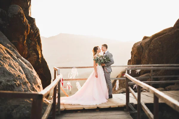 Feliz boda hermosa pareja novia y novio en el día de la boda al aire libre en la roca montañas. Feliz matrimonio pareja al aire libre en la naturaleza, luces suaves y soleadas — Foto de Stock