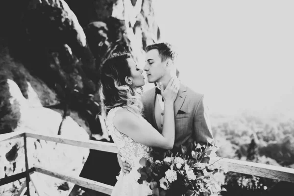 Feliz casamento bonito casal noiva e noivo no dia do casamento ao ar livre na rocha montanhas. Casamento feliz casal ao ar livre na natureza, luzes ensolaradas macias — Fotografia de Stock