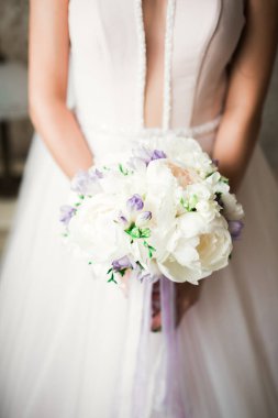 Gelin çiçekli büyük ve güzel bir düğün buketi tutuyor.