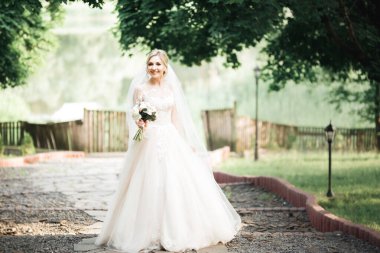 Gelin çiçekli büyük ve güzel bir düğün buketi tutuyor.