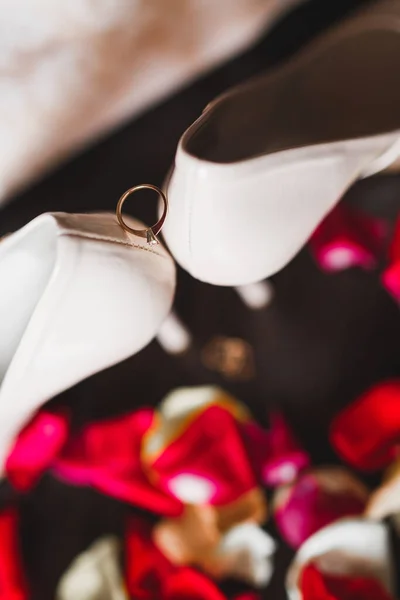 Hermosa imagen tonificada con anillos de boda en zapatos de boda contra el fondo de flores — Foto de Stock