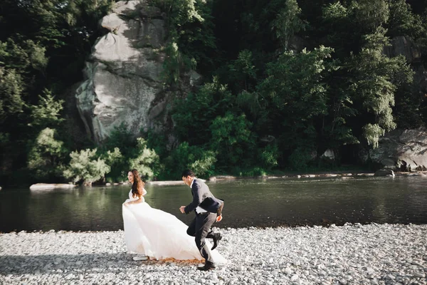 Pareja de boda, novio y novia corriendo, al aire libre cerca del río —  Fotos de Stock