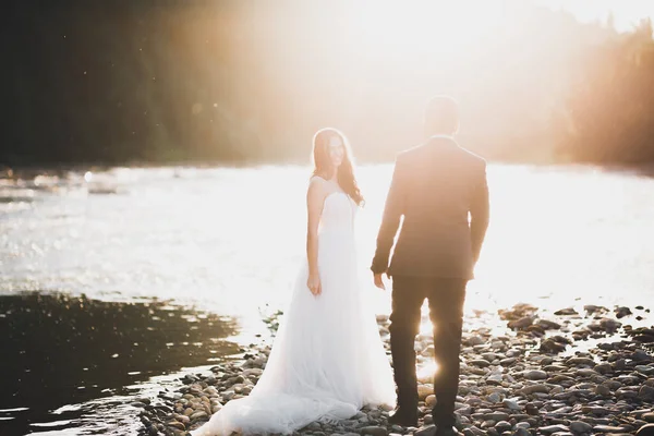 Elegante noiva loira feliz e lindo noivo no fundo de um belo rio nas montanhas — Fotografia de Stock