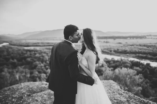 Vacker brud och brudgum omfamnar och kysser på sin bröllopsdag utomhus — Stockfoto