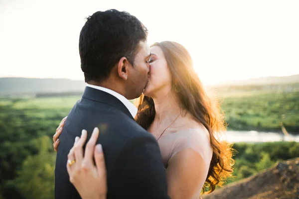 Прекрасные невеста и жених обнимаются и целуются на улице в день своей свадьбы — стоковое фото