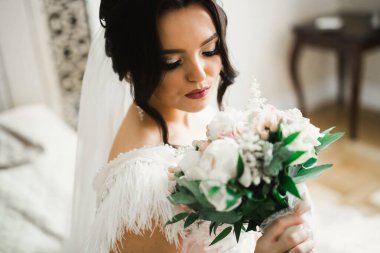 Gelin çiçekli büyük ve güzel bir düğün buketi tutuyor.