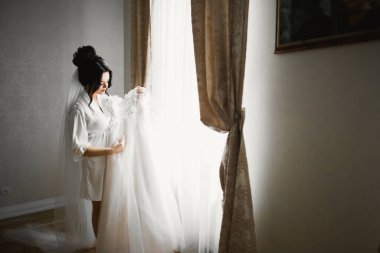 Beyaz elbiseli lüks gelin düğün törenine hazırlanırken poz veriyor.