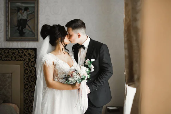 Прекрасные невеста и жених обнимаются и целуются в день свадьбы — стоковое фото