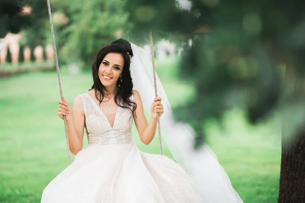 Schöne junge Luxusbraut im Brautkleid posiert im Park — Stockfoto