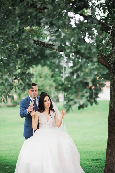 Man duwen zijn pasgetrouwde vrouw op een swing — Stockfoto