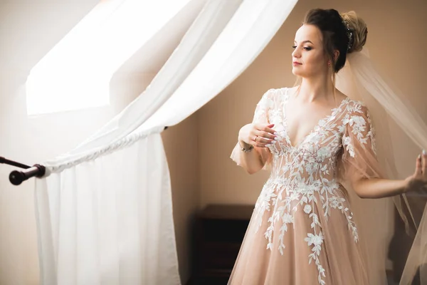 Hermosa novia con vestido de novia de moda con plumas con maquillaje de lujo deleite y peinado, estudio sesión de fotos interior — Foto de Stock