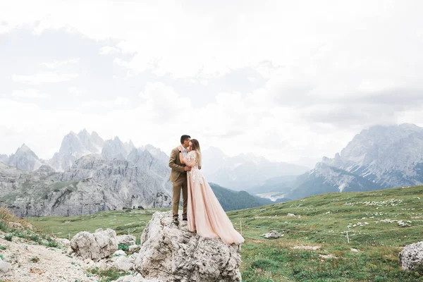 Linda noiva linda posando para noivo e se divertindo perto de montanhas com vista incrível, espaço para texto, casal de casamento — Fotografia de Stock