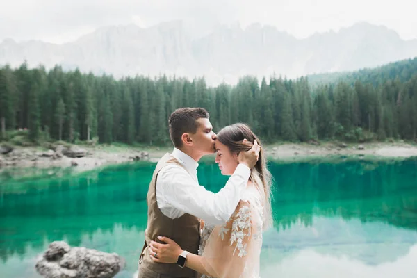 Hermosa pareja moderna besándose cerca de un lago en las montañas —  Fotos de Stock