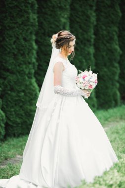 Gelin çiçekli büyük ve güzel bir düğün buketi tutuyor.