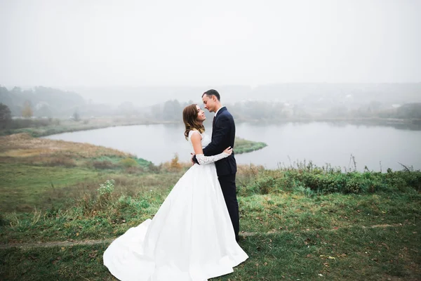 Romántico, cuento de hadas, feliz pareja recién casada abrazándose y besándose en un parque, árboles en el fondo — Foto de Stock