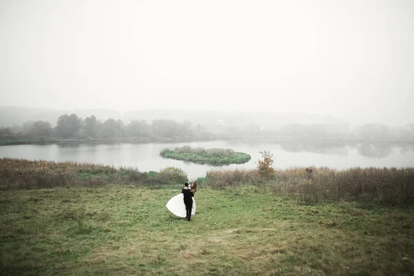 Hochzeitspaar in der Natur umarmt sich. Schöne Modell Mädchen in weißem Kleid. Mann im Anzug — Stockfoto