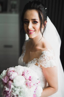 Çekici gelinin portresi, uzun saçlı, büyük buketli poz veren.