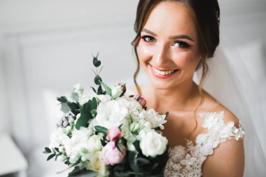 Lüks bir gelin, bir kız buketle poz veriyor ve gülümsüyor.