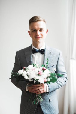 Yaka çiçeğiyle poz veren mutlu yakışıklı damat.