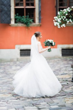 Gelin çiçekli büyük ve güzel bir düğün buketi tutuyor.