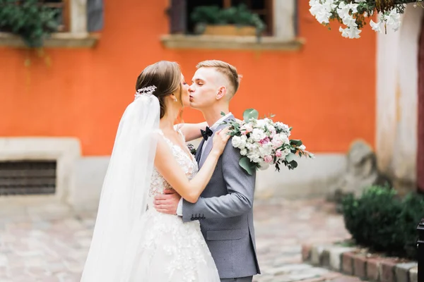 Vacker brud och brudgum omfamnar och kysser på sin bröllopsdag utomhus — Stockfoto