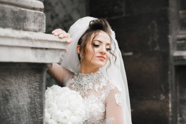 Gelin çiçekli büyük ve güzel bir düğün buketi tutuyor.