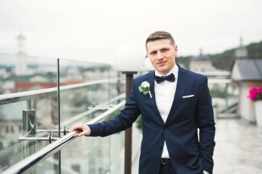 Yaka çiçeğiyle poz veren mutlu yakışıklı damat.