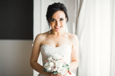 Gelin çiçekli büyük ve güzel bir düğün buketi tutuyor.