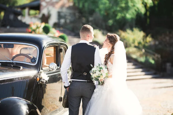 Весільна наречена і наречений, елегантна пара, що зупиняється біля ретро-весільного автомобіля — стокове фото